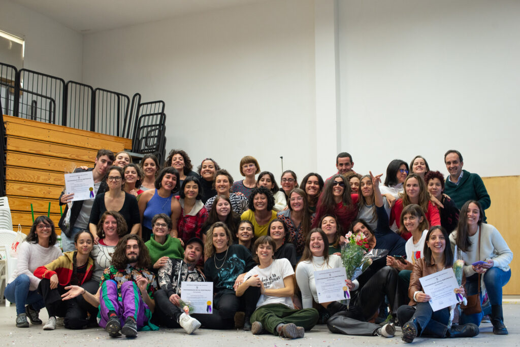 Imagen tipo foto de familia con estudiantes y docentes de la carrera en Danza Contermporánea y las personas egresadas con título en mano.