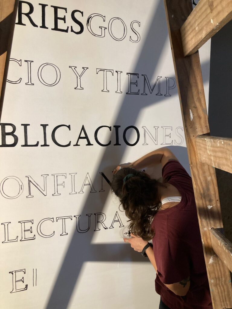 Fotografía de uno de los gráficos de la muestra, en el momento en que una estudiante está rellenando a mano las letras que lo conforman.