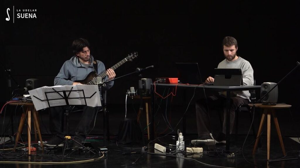 Fotografía tomada en los estudios de la FIC, en la que se ve a ambos interpretes en pleno desarrollo de su tarea, rodeados de instrumentos  y aparatos técnicos.  