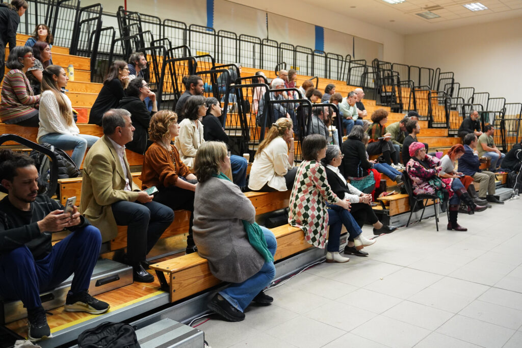 Fotografía donde se ven las gradas del salón 318 con público asistente al evento