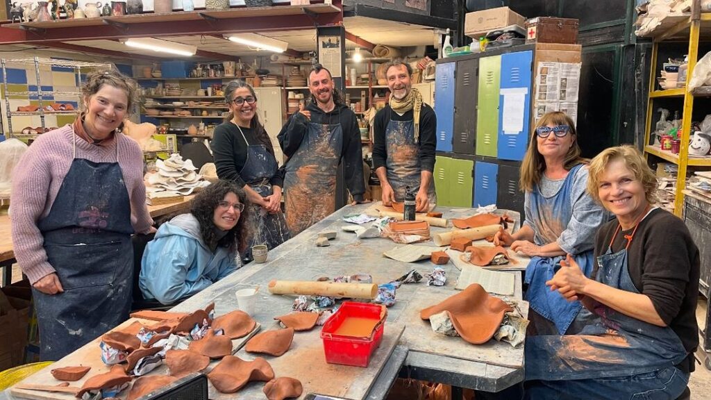 Fotografía de la artista Adela Casacuberta en el Taller de Artes del Fuego junto a varios colaboradores y voluntarios durante la producción de las piezas de cerámica de su obra "Hongos rosados en los jardines del museo"